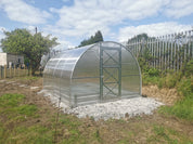 Arch-style greenhouse with 4mm polycarbonate panels on gravel foundation in backyard