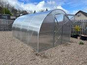 Polycarbonate arch greenhouse with reinforced steel door installed on gravel base