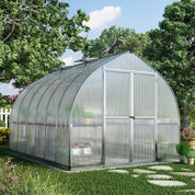 Barn-style polycarbonate greenhouse with double doors in landscaped backyard garden