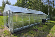 Large gable greenhouse with polycarbonate panels and galvanized steel frame with roof vent in backyard