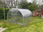 Galvanized steel greenhouse with polycarbonate panels installed in residential backyard