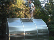 Man standing on greenhouse roof demonstrating heavy-duty structural strength and durability
