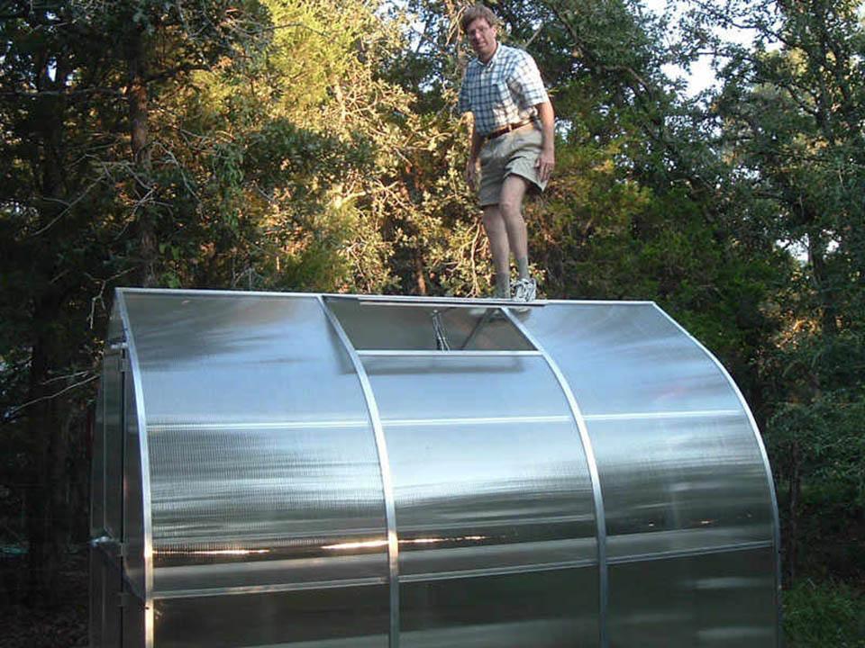 Man standing on greenhouse roof demonstrating heavy-duty structural strength and durability