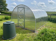 Arch-style polycarbonate greenhouse on grass lawn in rural countryside setting