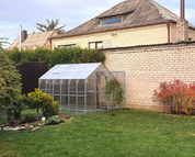 Polycarbonate greenhouse installed in residential backyard garden with lawn
